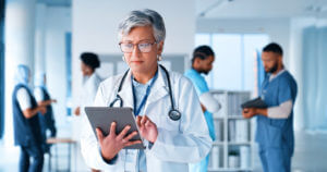 A picture of a mature woman doctor on a tablet at the hospital for weekend healthcare services on Sunday.