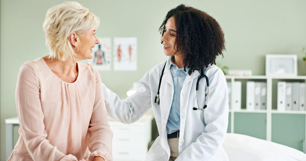 Image of a senior woman and a female primary care physician discussing during a consultation.