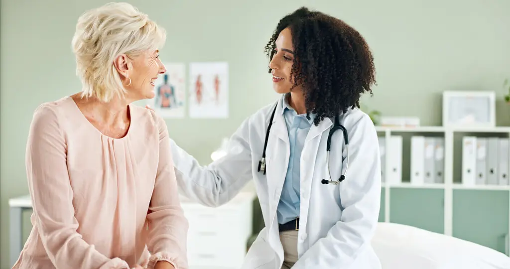 Image of a senior woman and a female primary care physician discussing during a consultation.