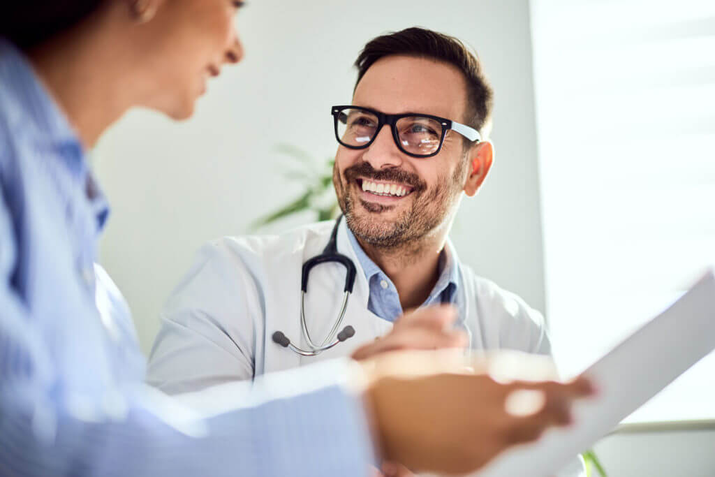Smiling Male Primary Care Physician Conversing with a Patient in a Bright Office Setting.