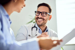 Smiling Male Primary Care Physician Conversing with a Patient in a Bright Office Setting.
